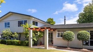 A two-story house with a covered patio and a well-maintained lawn. - Tasman Tranquility Cozy family home (Motueka)
