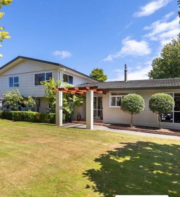 A two-story house with a covered patio and a well-maintained lawn.