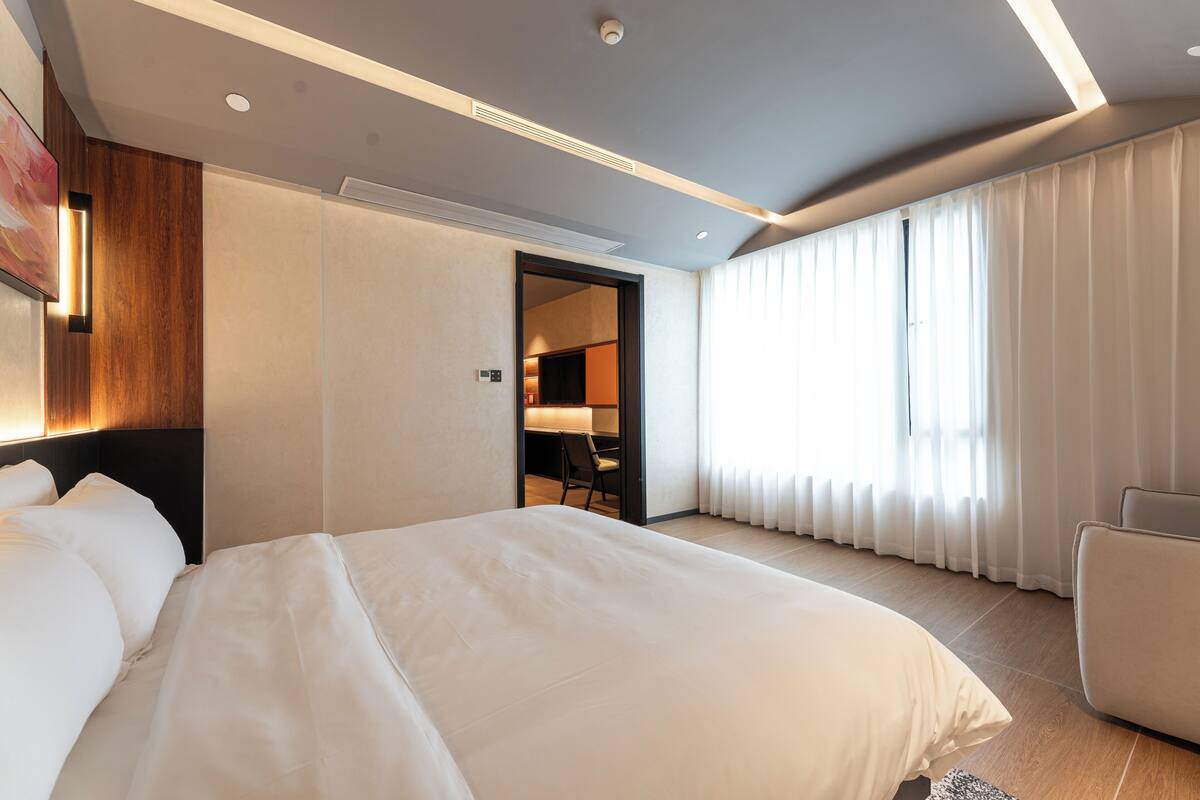 A modern hotel room with a large bed, a desk, and a chair.