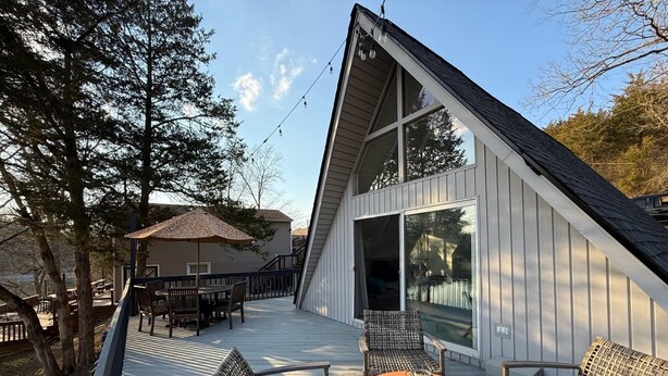 Uma casa moderna com um deck espaçoso, móveis de exterior e porta de vidro que dá para um alpendre coberto.