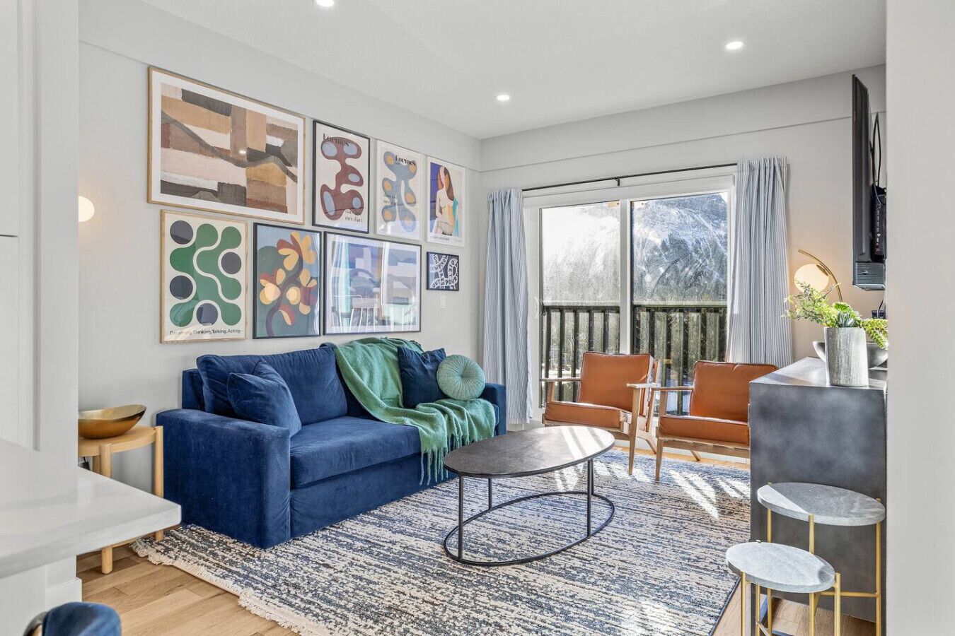 Un salon moderne avec un canapé bleu, une table basse ronde et un coin repas comprenant une table et des chaises blanches.
