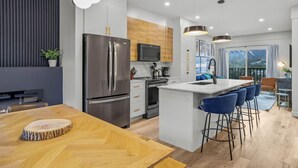 A modern kitchen with a central island, stainless steel appliances, and a dining area with a wooden table.