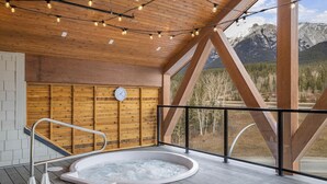 A hot tub on a wooden deck with a wooden wall and a clock.