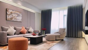 Ein modernes Wohnzimmer mit einer Couch, einem Sessel, einem Hocker und einem Couchtisch.