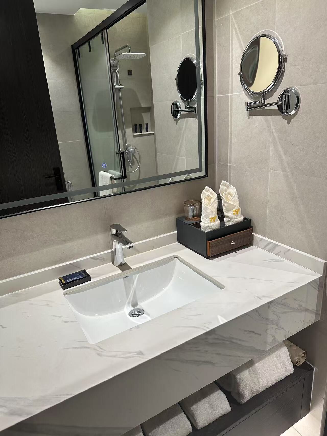 A modern bathroom with a large mirror, a sink, and a shower.