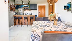 A modern kitchen with a central island, bar stools, and a dining area with a table and chairs. - Apartment located near the beach and the shopping mall. (MACEIÓ)