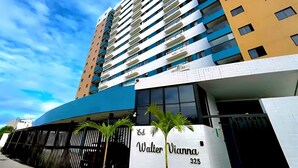 Een hoog hotelgebouw met een modern ontwerp, met een opvallende ingang en een bord waarop 'Walter Vianna 325' staat.