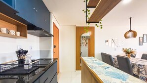 A modern kitchen with a black countertop, wooden cabinets, and a built-in stove. - Apartment located near the beach and the shopping mall. (MACEIÓ)