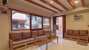 A spacious living area with wooden furniture, large windows, and a tiled floor. - ye layeku boutique hotel pvt ltd (Kathmandu)