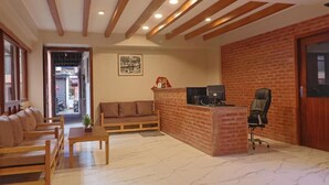 A reception area with a brick counter, a sofa, a desk, and a chair. - ye layeku boutique hotel pvt ltd (Kathmandu)