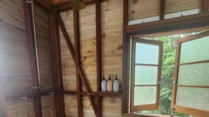 A rustic bathroom with a freestanding bathtub, wooden beams, and a window with a view of greenery. - Solara Dome Off Grid Luxury and Stillness at Shanlyn Farm (Traveston)