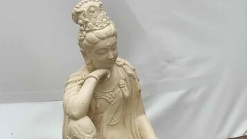 Una estatua blanca de una figura sentada sobre una plataforma de madera.