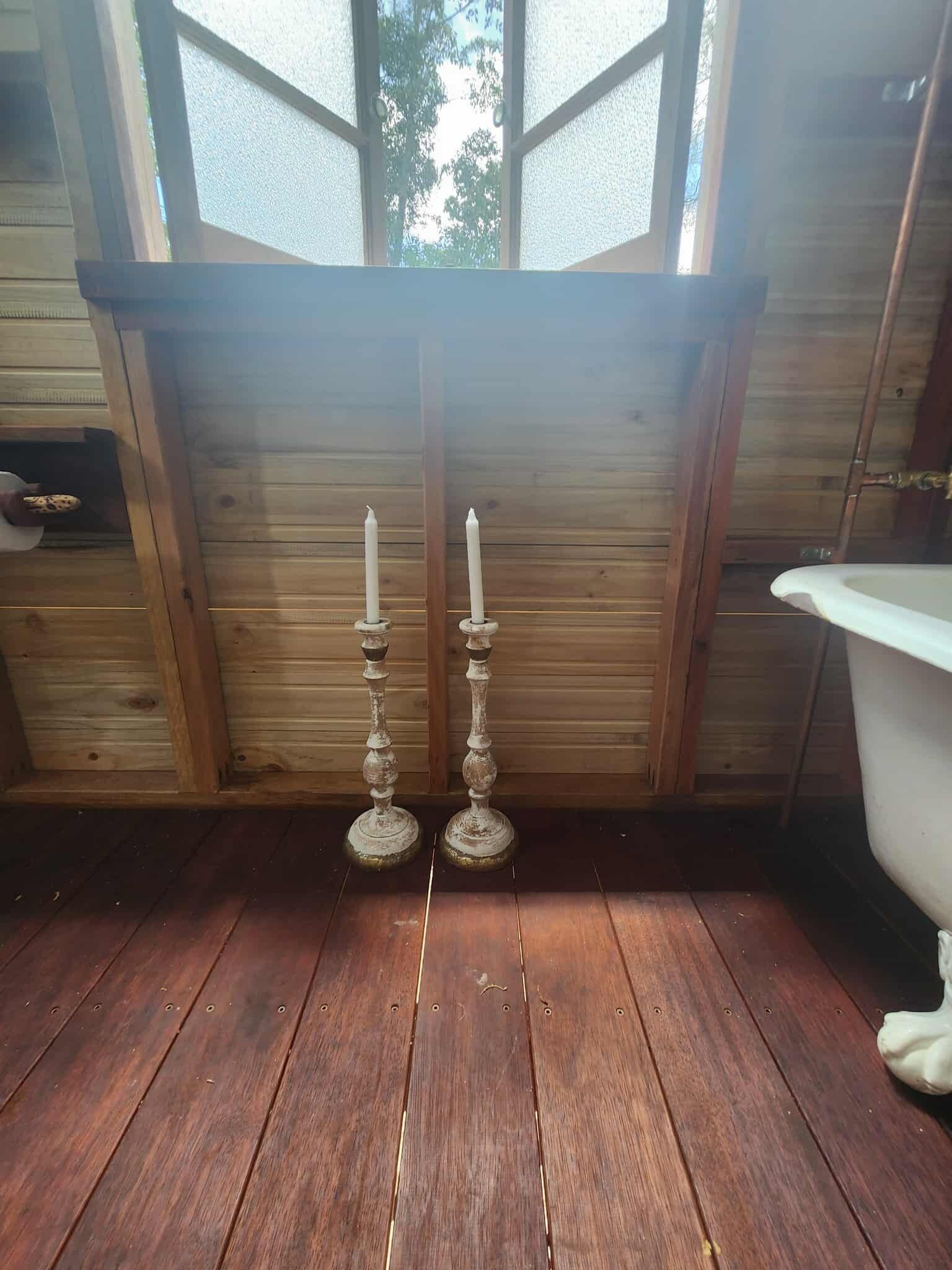 L’intérieur d’un chalet en bois, avec un plancher en bois, une fenêtre et une baignoire blanche.