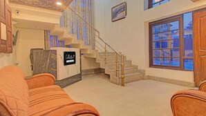 A spacious lobby with a marble reception desk, a staircase, and a large window with a view of a snowy landscape. - Classic Main Street Inn (Srinagar)