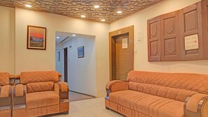 A reception area with a reception desk, two sofas, a wooden panel wall, and a ceiling with a geometric pattern. - Classic Main Street Inn (Srinagar)