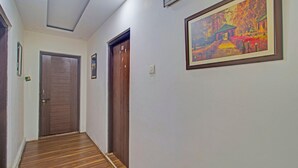 A hallway with wooden flooring, a door, and a framed painting on the wall. - Classic Main Street Inn (Srinagar)