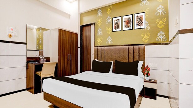 Ein modernes Hotelzimmer mit einem großen Bett, einem Schreibtisch mit Stuhl, einem Kleiderschrank und einem Schminktisch mit Spiegel.
