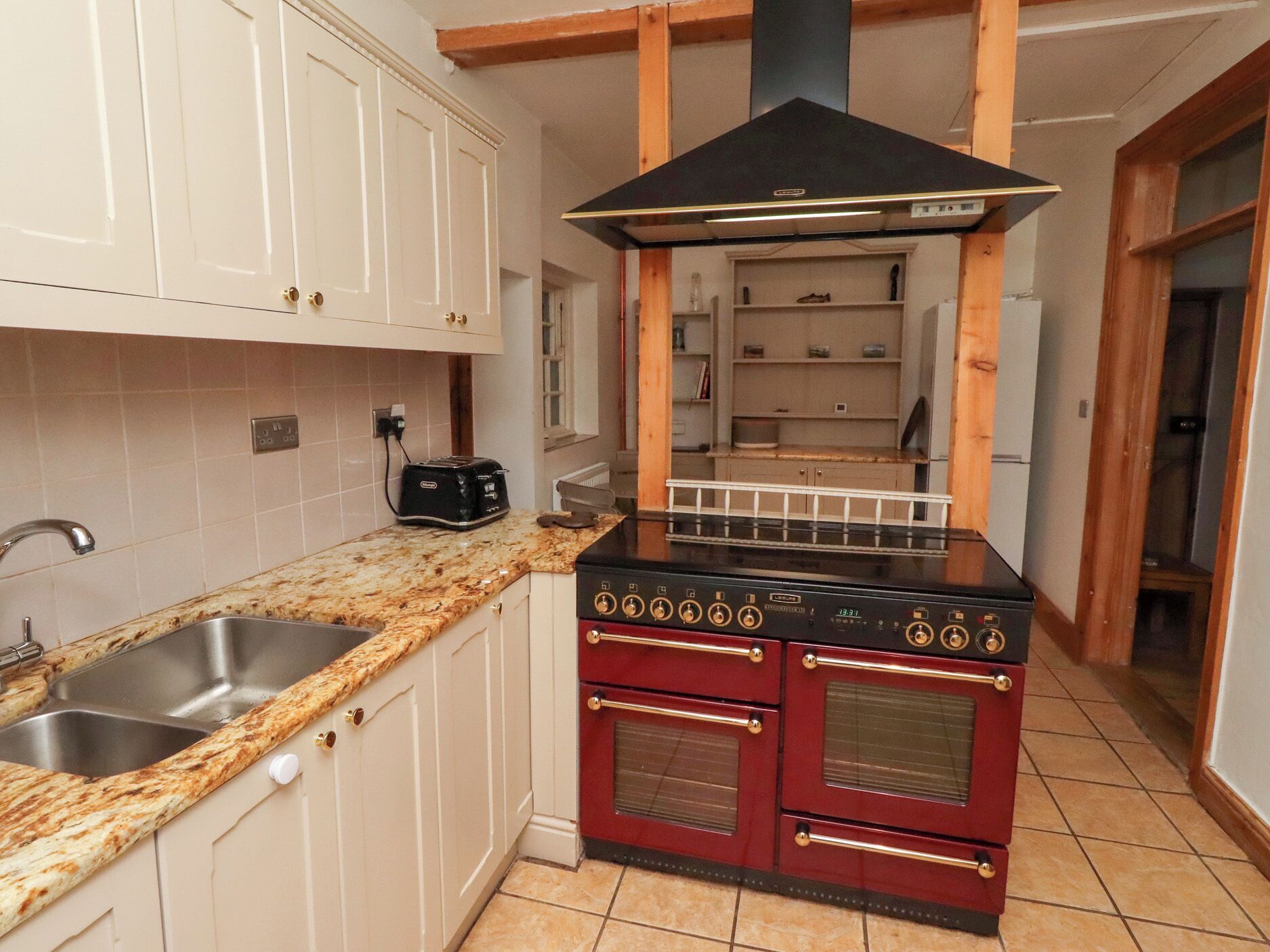 A kitchen with white cabinets, a granite countertop, a black stove, and a red oven.