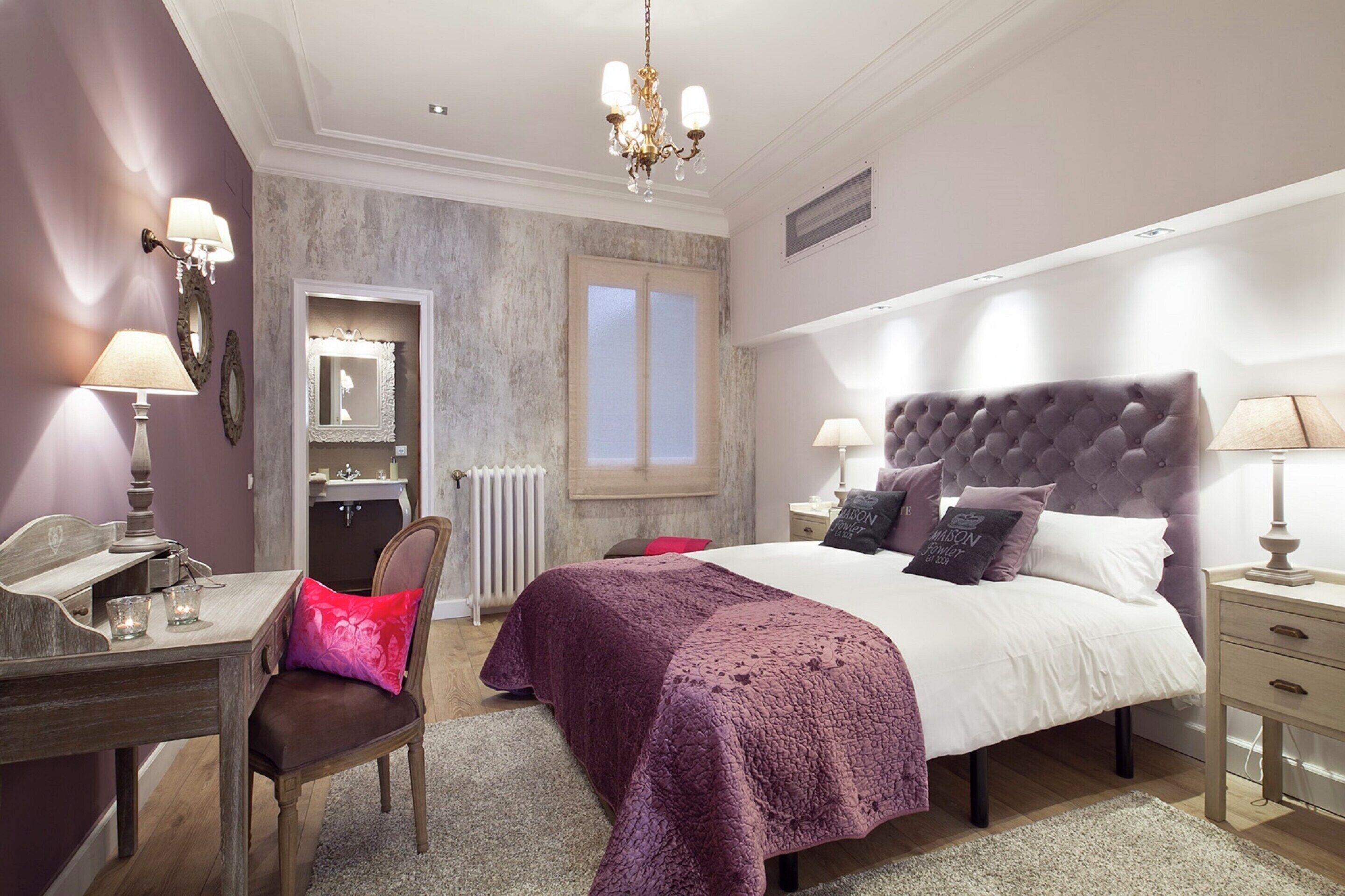 Een slaapkamer met een groot bed, nachtkastjes, een bureau en een stoel.