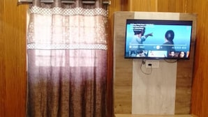 A room with wooden paneling, a mounted flat-screen TV, and an air conditioning unit. - New Hotel Tuk Tuk Palace (Ranchi)