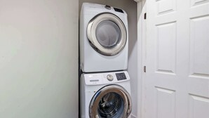 A stacked washer and dryer unit in a laundry room with a white door.
