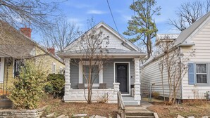 A two-story house with a front porch, stone steps, and a small garden area.