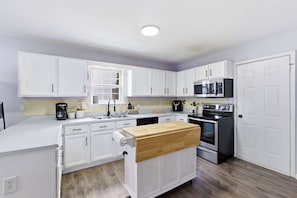 A modern kitchen with white cabinets, a wooden countertop, a built-in oven, and a microwave. - Spacious Louisville getaway with private backyard! (Louisville)