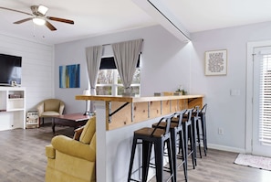 A modern kitchen with a bar area, wooden stools, and a ceiling fan. - Spacious Louisville getaway with private backyard! (Louisville)