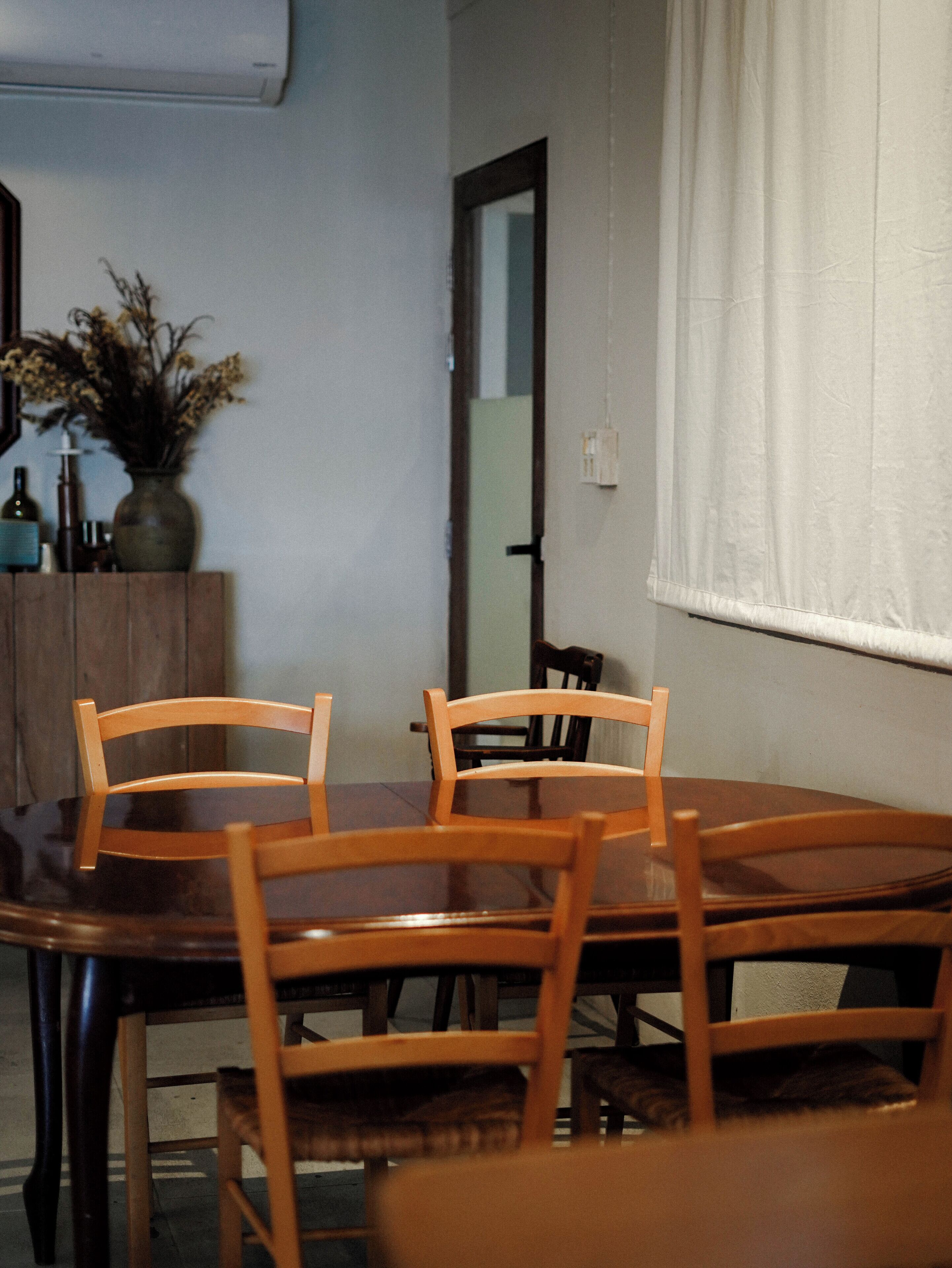 Un comedor con una mesa y sillas de madera, un armario con botellas y un espejo en la pared.