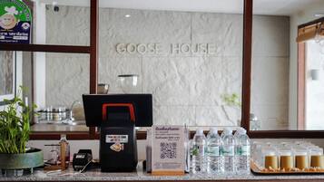 A hotel reception area with a counter, a Visa card reader, a QR code sign, and bottled water.