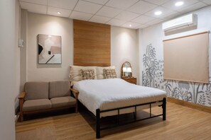 A bedroom with a bed, a sofa, a nightstand, and an air conditioning unit. - THE GOOSE HOUSE UBON  (Ubon Ratchathani)