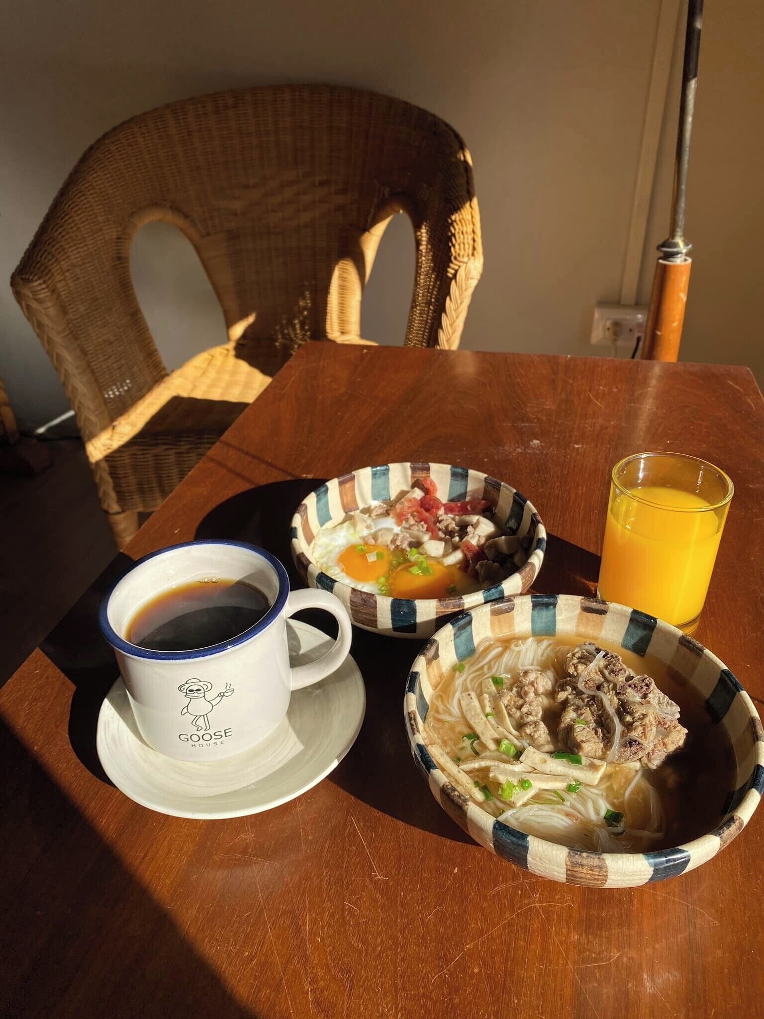 A table with a cup of coffee, two bowls of food, and a glass of orange juice.