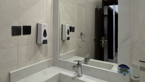 Ein modernes Badezimmer mit einem großen Waschbecken, einem Spiegel und einer Wandleuchte.