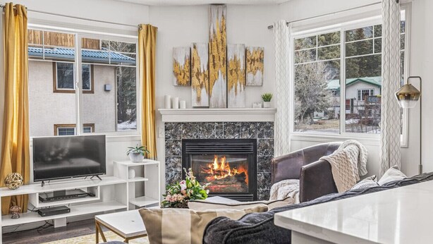 Una sala de estar moderna con chimenea, un televisor de pantalla plana y una zona de estar confortable.