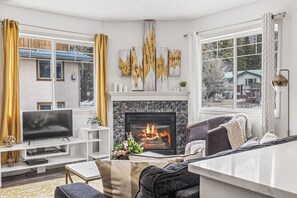 A modern living room with a fireplace, a flat-screen TV, and a comfortable seating area.