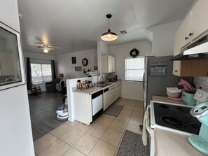 A compact kitchen with white cabinets, a built-in oven, and a microwave. There is a small island with a sink and a window above it. - Beautifully updated 3bedroom, 2.5bathroom home in a quiet Surprise neighborhood (Surprise)
