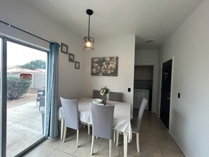 A dining area with a table set for four, a hanging light fixture, and a view of the outside through a sliding glass door. - Beautifully updated 3bedroom, 2.5bathroom home in a quiet Surprise neighborhood (Surprise)