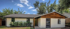 A modern single-story house with a sloped roof, a front porch, and a small attached garage. - Stylish 4BR Retreat in Denton | Sleeps 10 UNT TWU (Denton)