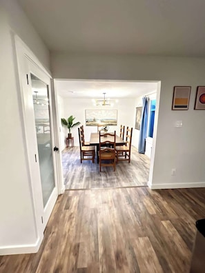 A dining area with a wooden table and chairs, a potted plant, and a painting on the wall. - Stylish 4BR Retreat in Denton | Sleeps 10 UNT TWU (Denton)