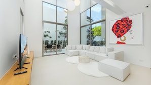 A modern living room with a white sectional sofa, a round coffee table, and a flat-screen TV on a wooden stand. - LuxPride Villas Private Pool Tropiclook (Si Sunthon)