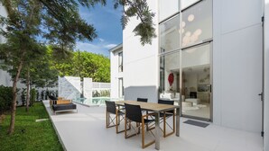 A modern outdoor patio with a dining table and chairs, a small pool, and a glass door leading to a living area. - LuxPride Villas Private Pool Tropiclook (Si Sunthon)
