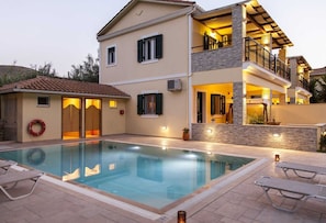 A two-story house with a swimming pool, outdoor seating, and a balcony. - Azalea Villas (Lefkada)