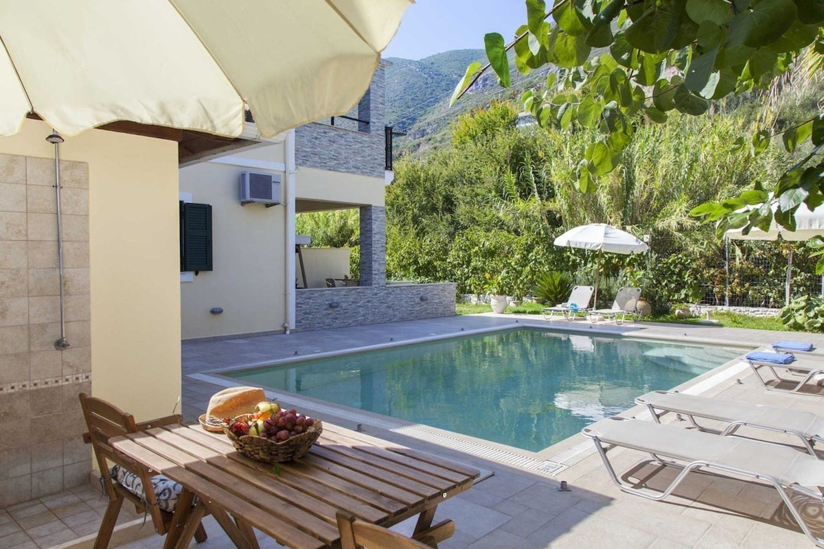 A poolside area with a table, chairs, and umbrellas.