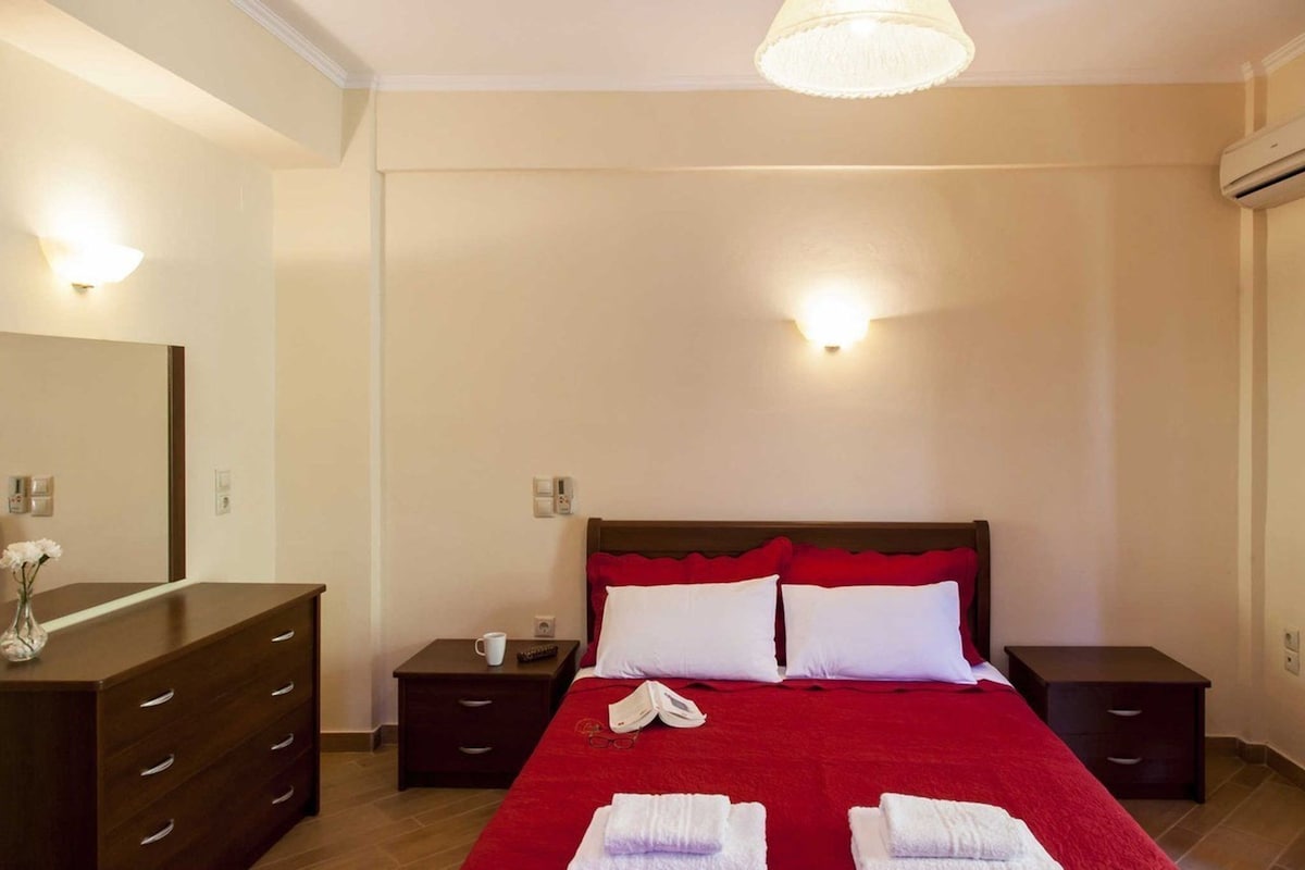 A hotel room with a large bed, two bedside tables, a dresser, and a mirror.
