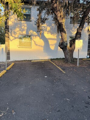 A parking lot with a white building in the background, a tree with Spanish moss, and a sign indicating parking restrictions. - Hidden Gem in Tampa. Cozy, comfortable and great location (Tampa)