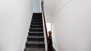 A staircase with dark carpeted steps and a wooden handrail with a rounded top. - Standard Double Room (Salford)