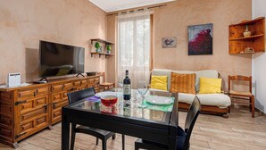 Una sala de estar con televisor, aparador de madera, mesa de comedor y un sofá.