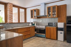 A modern kitchen with wooden cabinets, a built-in oven, a microwave, and a refrigerator. - Matthew Villa Umalas (Kerobokan)
