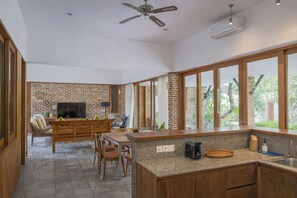 A spacious kitchen with a large island, wooden cabinets, and a brick accent wall. - Matthew Villa Umalas (Kerobokan)