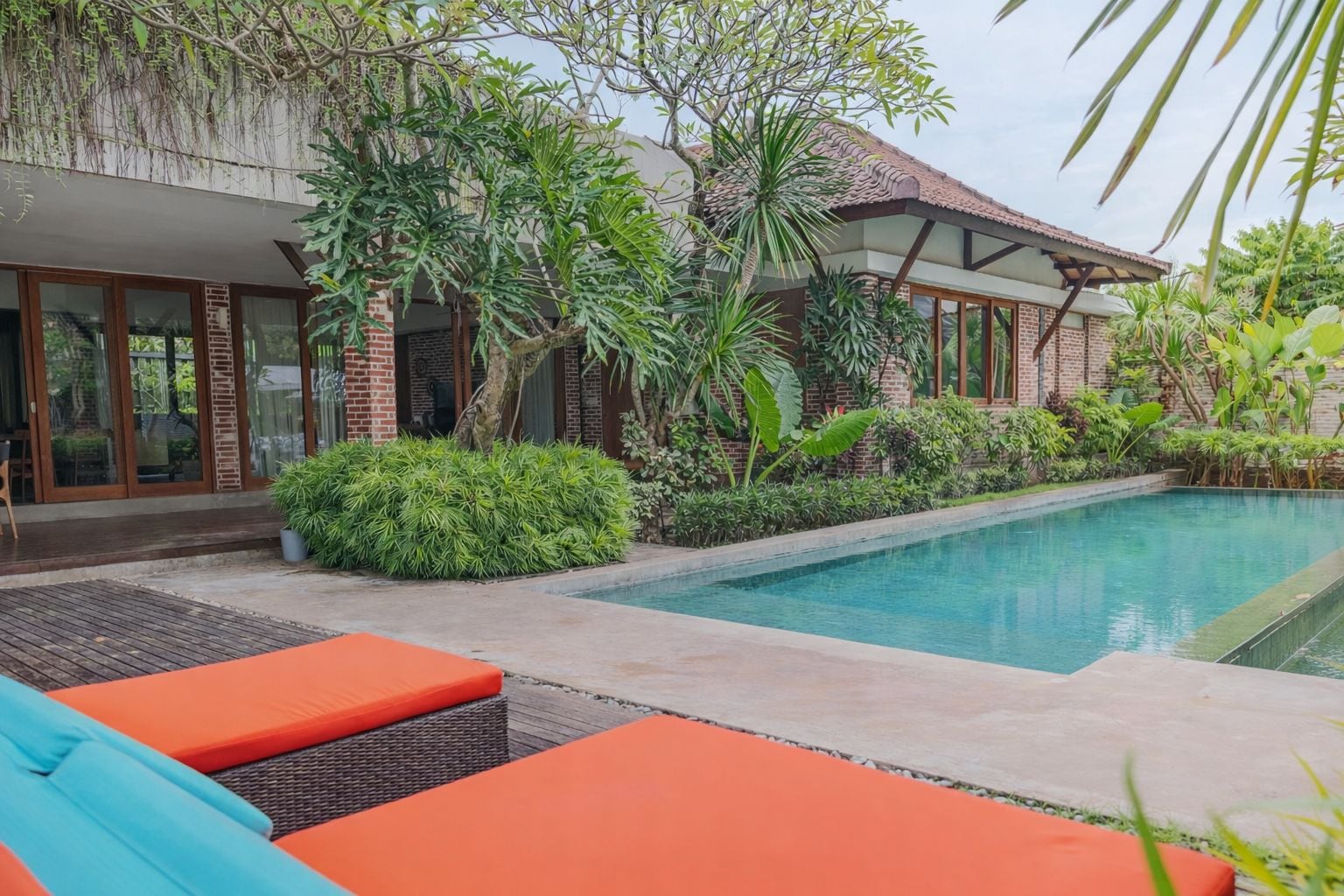 A modern house with a swimming pool, surrounded by lush greenery and outdoor seating.